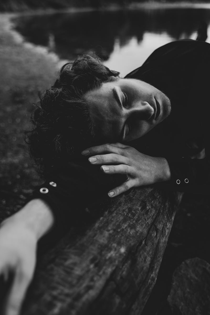 Artistic black and white portrait of a man sleeping outdoors, exuding a serene mood.